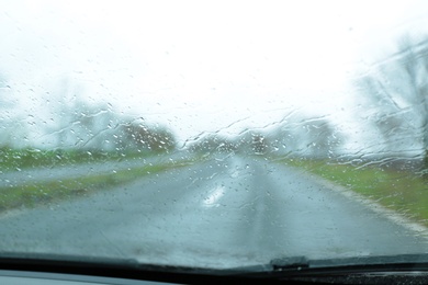 Photo of Blurred view of suburban road through wet car window. Rainy weather