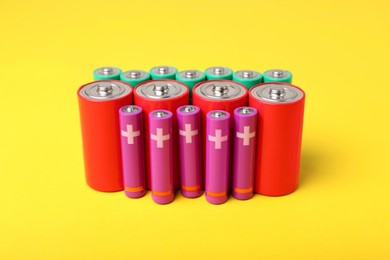 Photo of Batteries of different sizes on yellow background