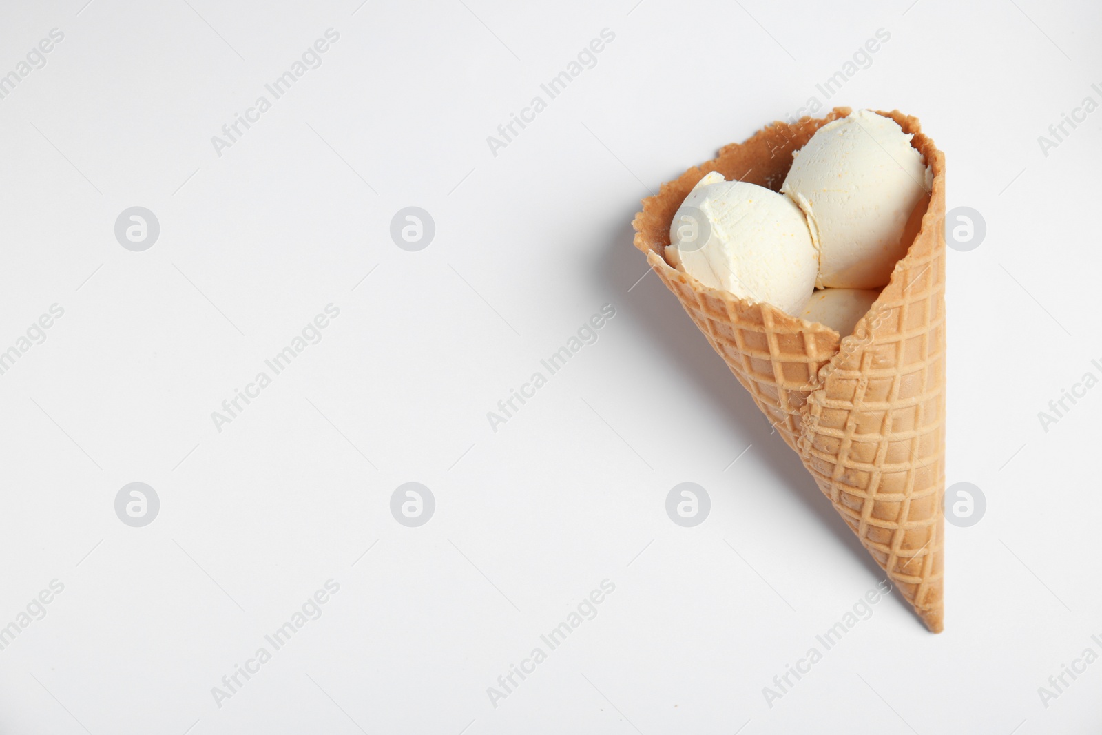Photo of Delicious vanilla ice cream in wafer cone on white background, top view