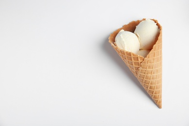 Delicious vanilla ice cream in wafer cone on white background, top view