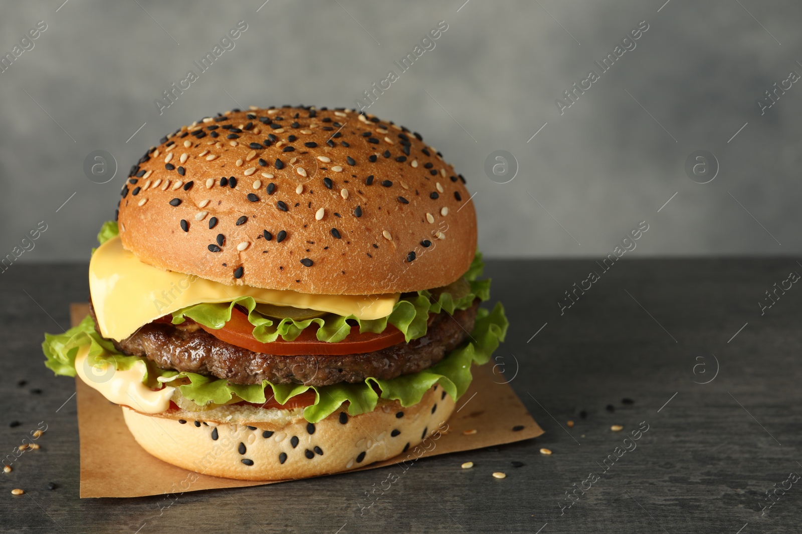 Burger with delicious patty on gray table, space for text Photo of Burger with delicious patty on gray table, space for text