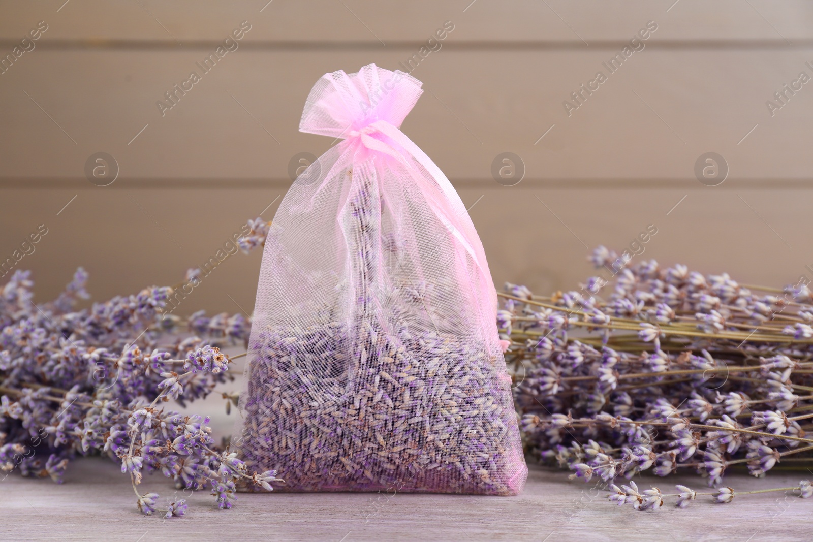 Photo of Scented sachet and dried lavender flowers on wooden table, closeup