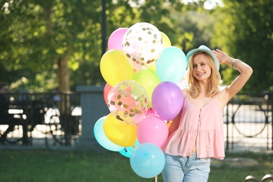 Young woman with colorful balloons outdoors on sunny day