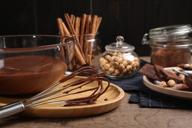 Bowl and whisk with chocolate cream on wooden table. Space for text