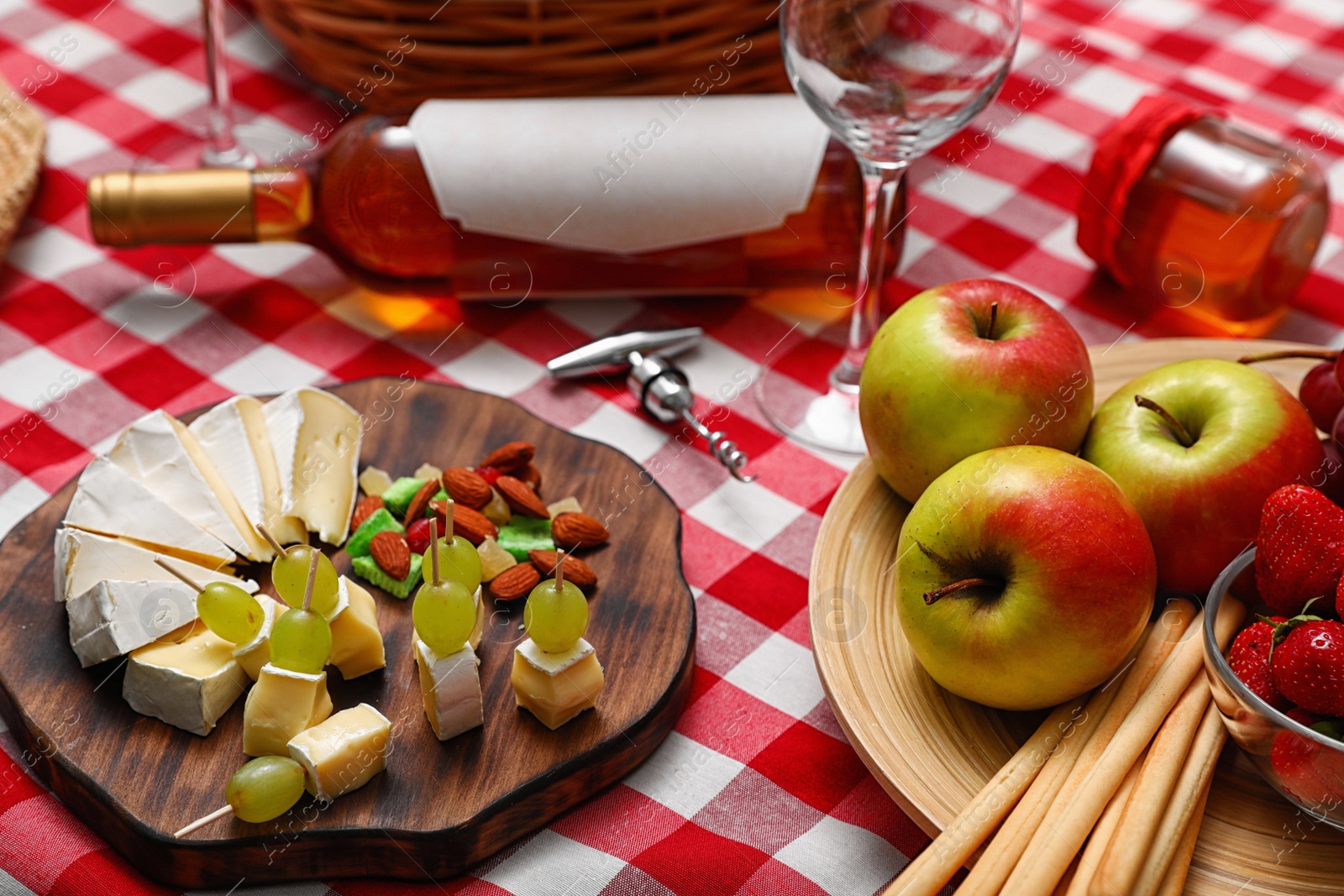 Photo of Composition with cheese, fruits and wine on checkered picnic blanket