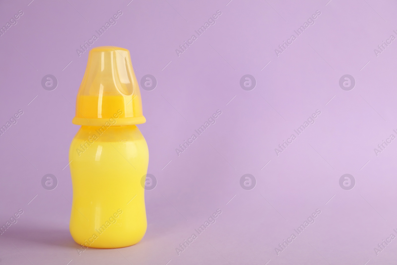 Photo of Feeding bottle with infant formula on lilac background, space for text. Baby milk