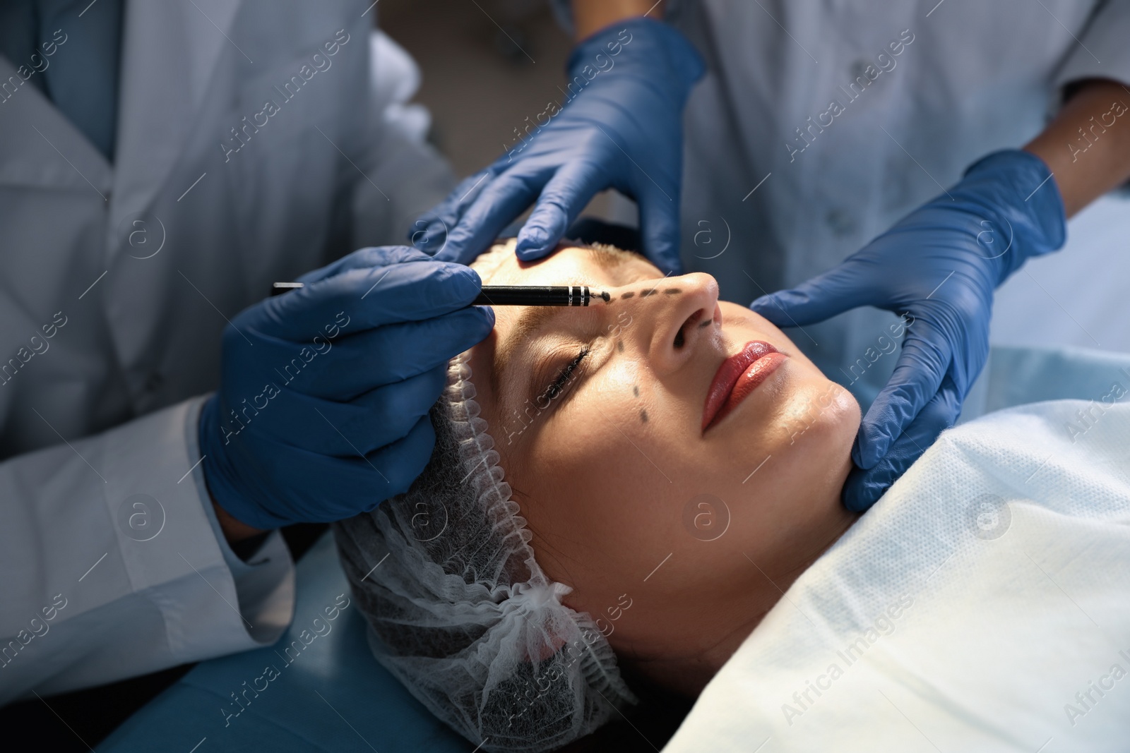 Photo of Doctor and nurse preparing female patient for cosmetic surgery in clinic