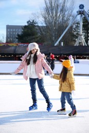 Mother and daughter spending time together at outdoor ice skating rink