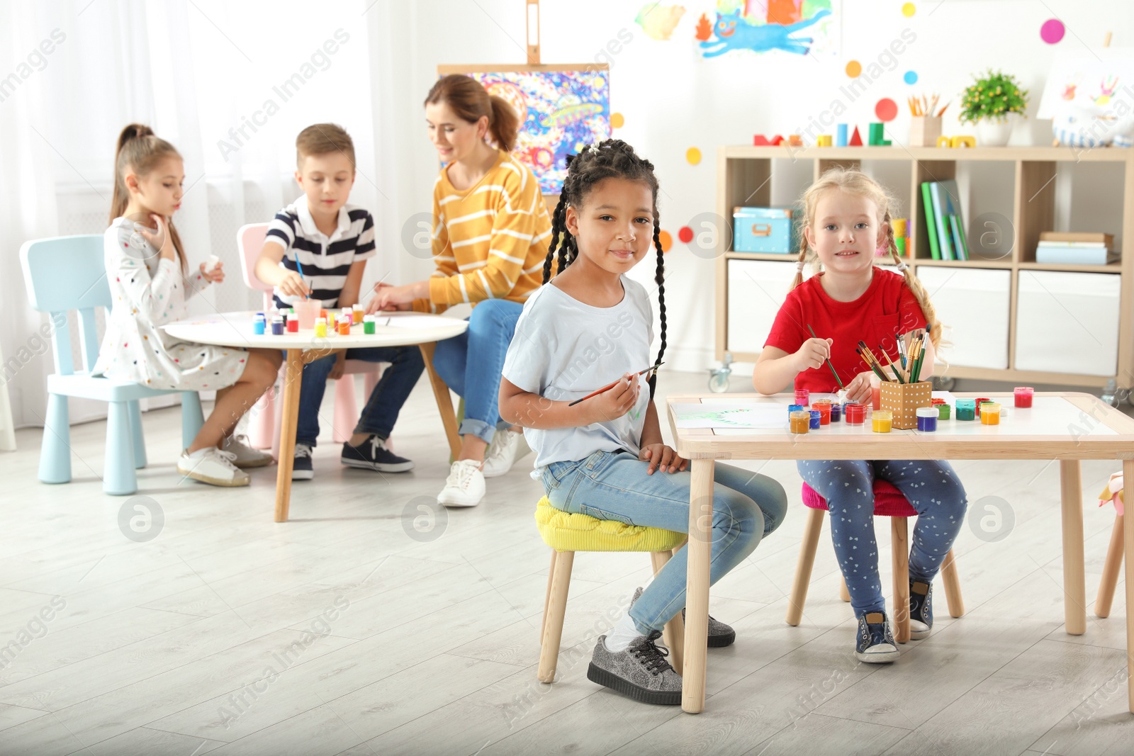 Photo of Children with female teacher at painting lesson indoors