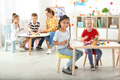 Children with female teacher at painting lesson indoors