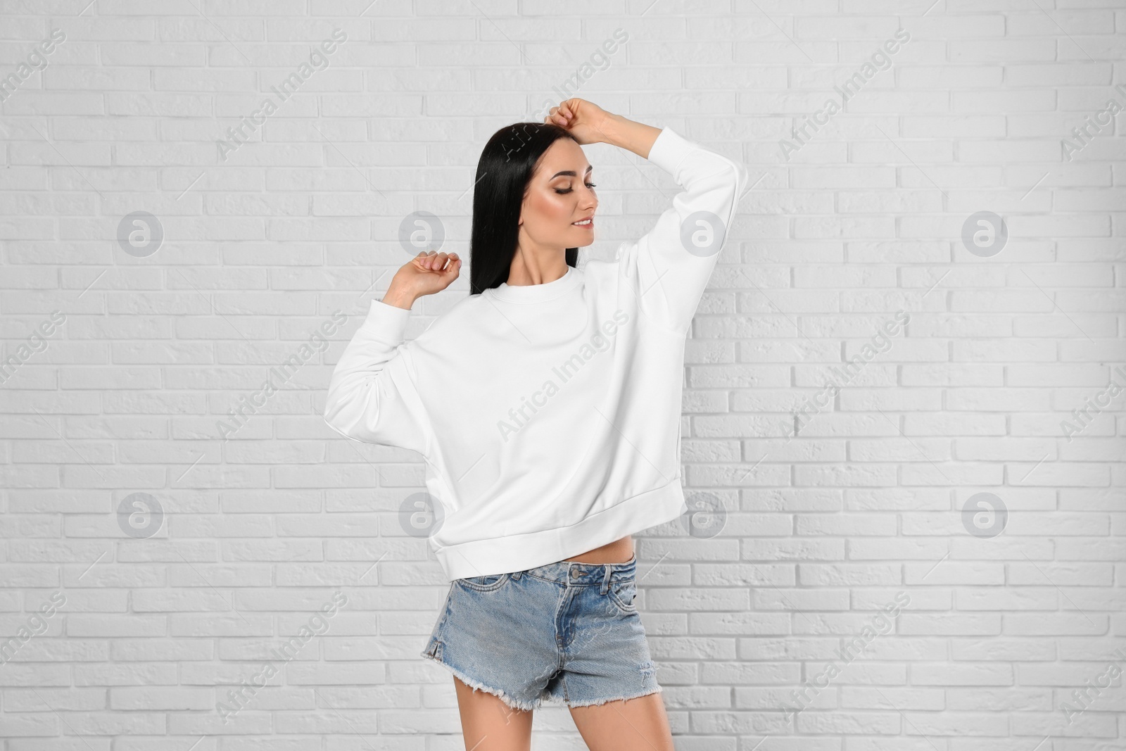 Photo of Portrait of young woman in sweater at brick wall. Mock up for design