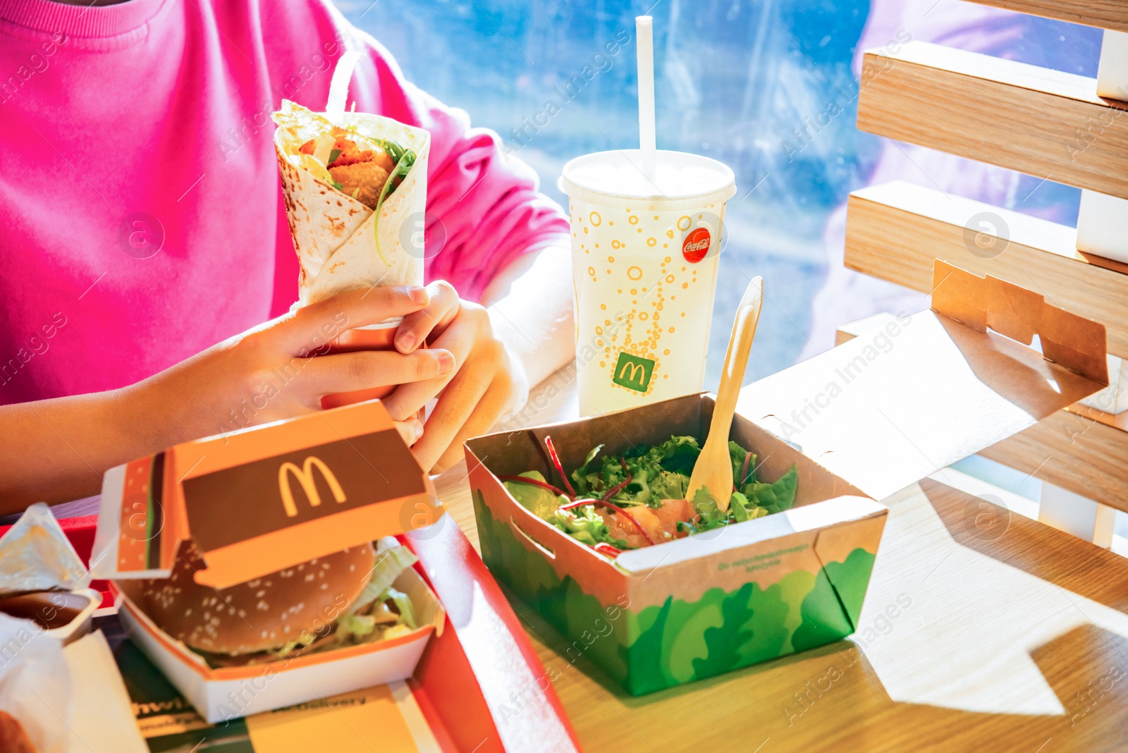 Photo of WARSAW, POLAND - SEPTEMBER 16, 2022: Woman eating roll with chicken in McDonald's cafe, closeup