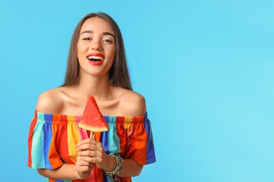 Beautiful young woman posing with watermelon on color background