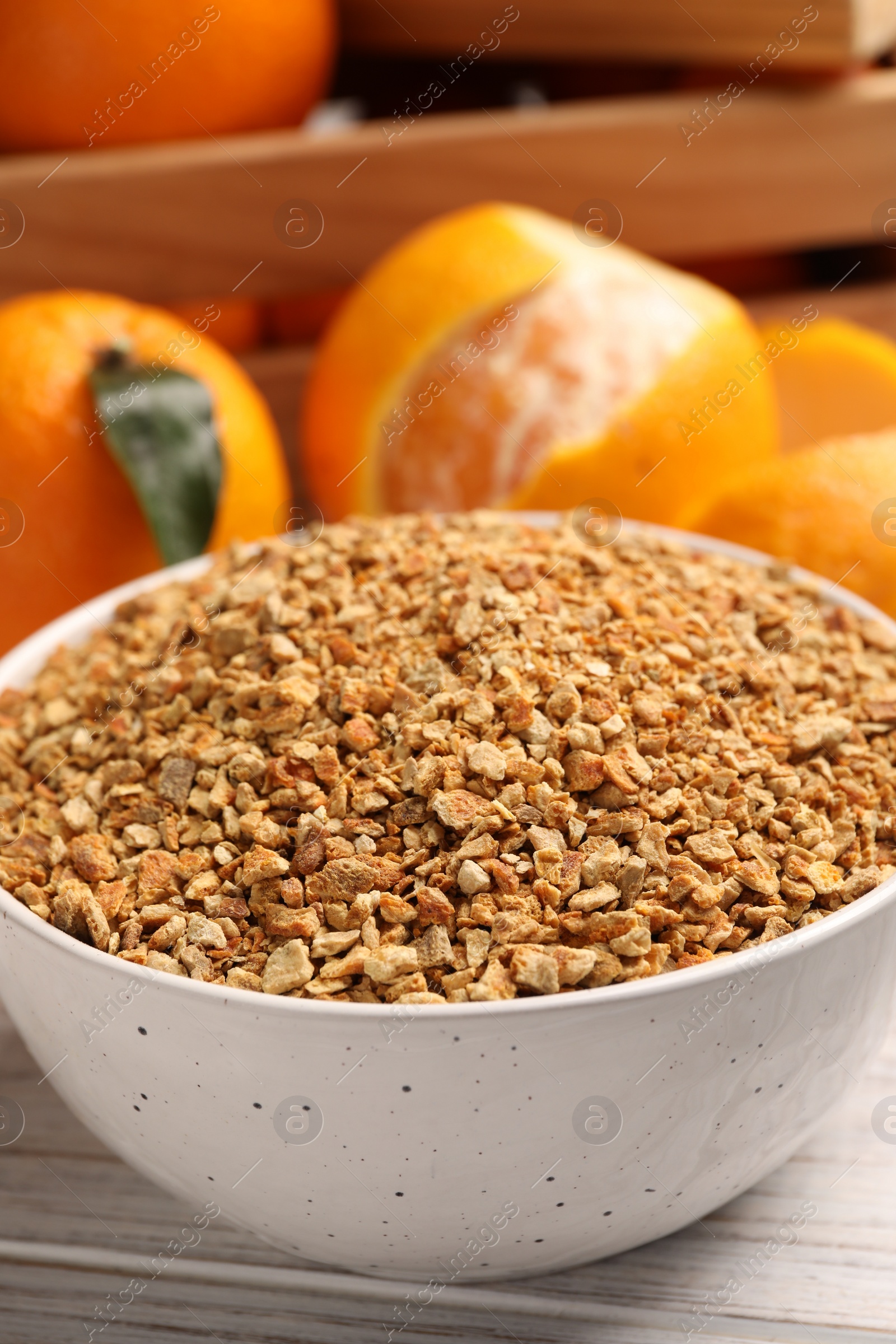 Photo of Bowl with dried orange seasoning zest and fruits on white wooden table, closeup
