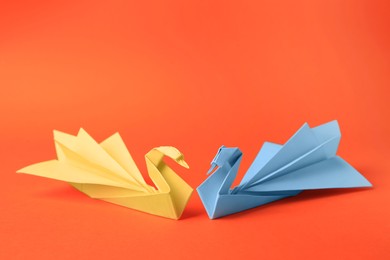 Photo of Origami art. Beautiful paper swans on orange background