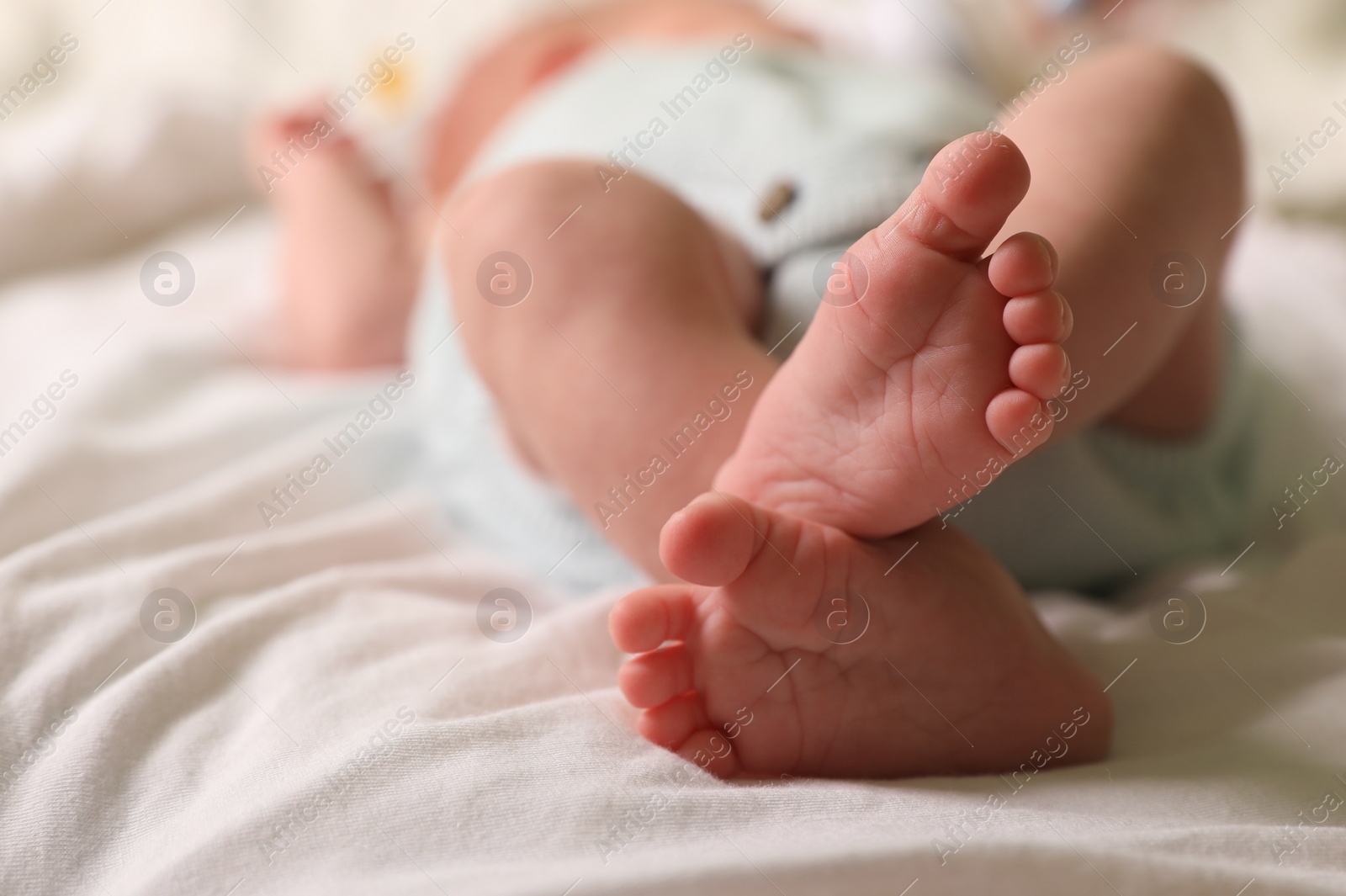 Photo of Cute newborn baby lying on bed, closeup of legs. Space for text