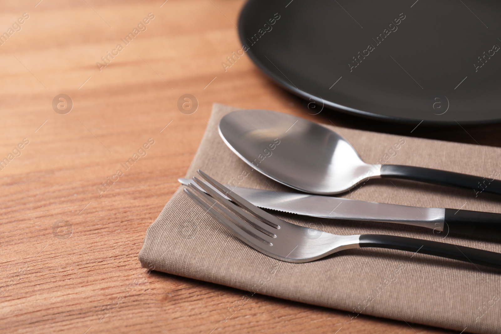 Photo of Table setting with cutlery, napkin and plate on wooden background, closeup