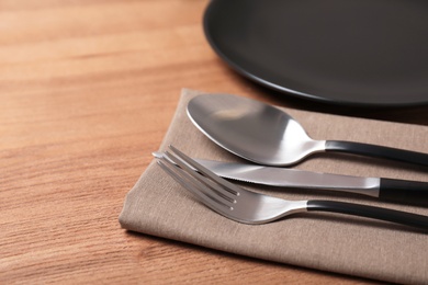 Photo of Table setting with cutlery, napkin and plate on wooden background, closeup