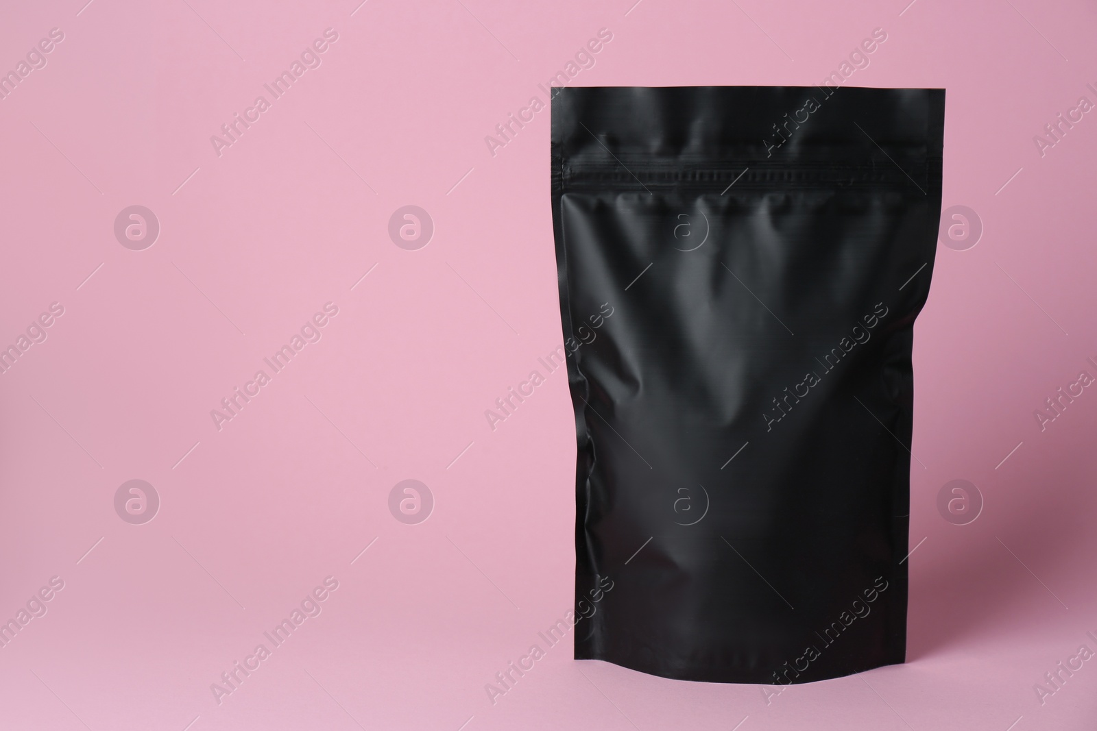 Photo of One blank foil package on pink background. Space for text