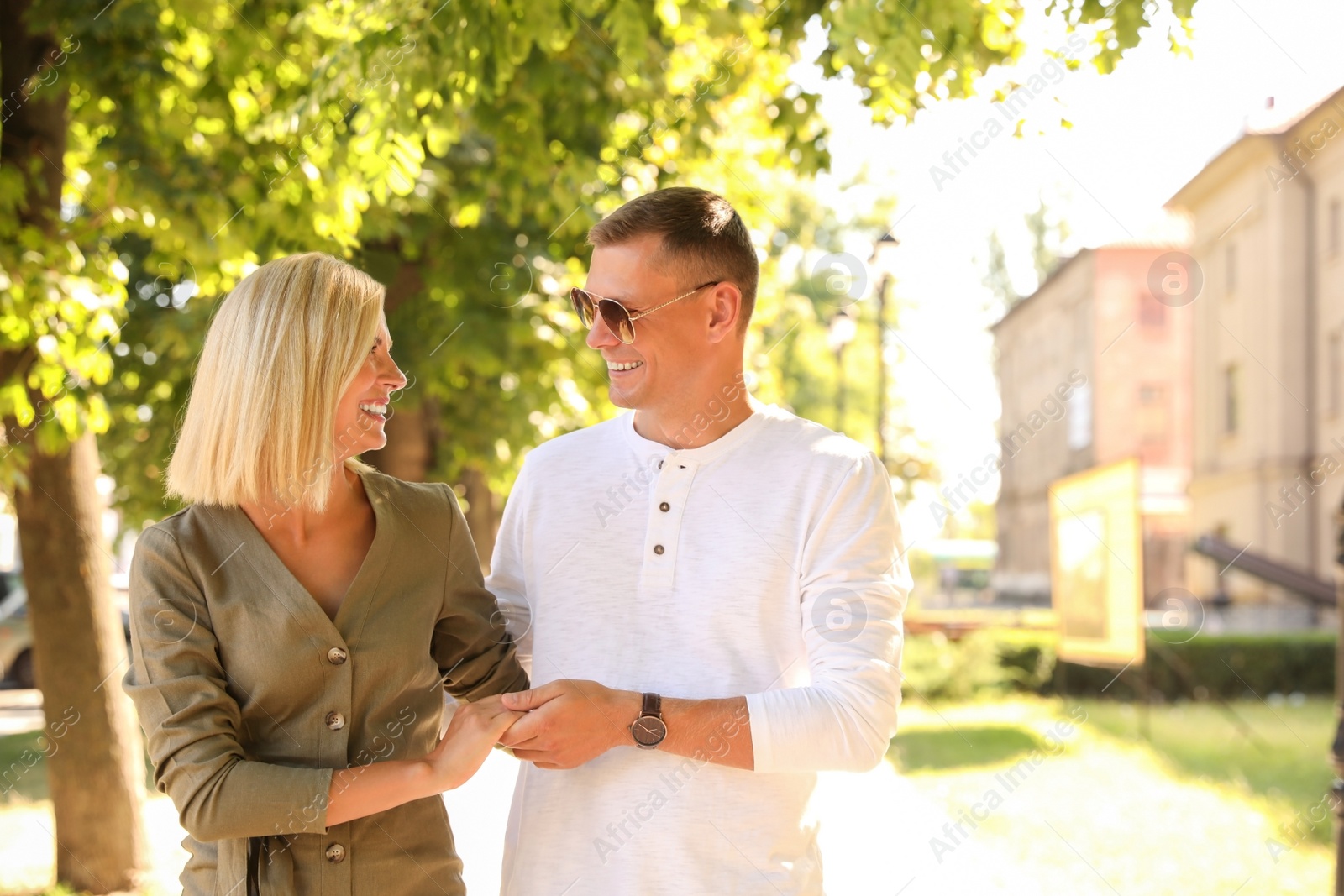 Photo of Happy couple walking along city street on summer day