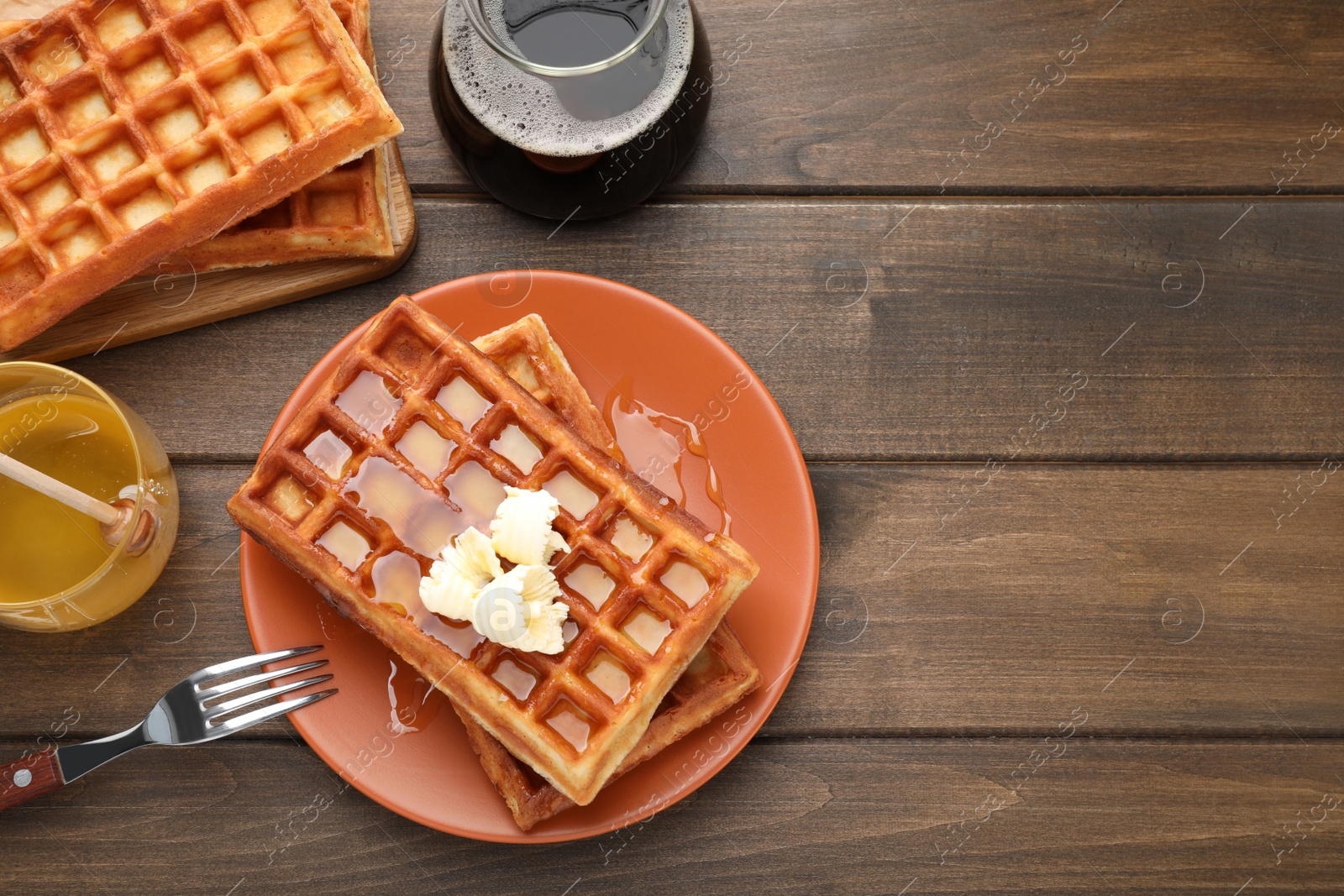 Photo of Plate of delicious Belgian waffles with honey and butter served on wooden table, flat lay. Space for text