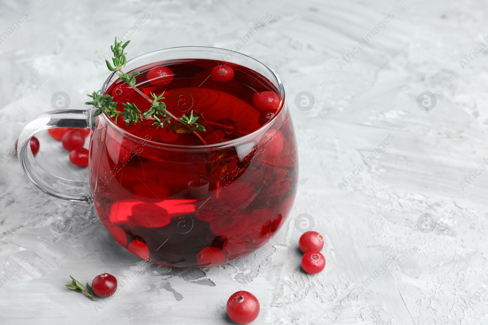 Photo of Delicious cranberry tea with thyme and berries on grey table, closeup. Space for text