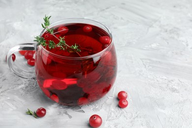 Photo of Delicious cranberry tea with thyme and berries on grey table, closeup. Space for text