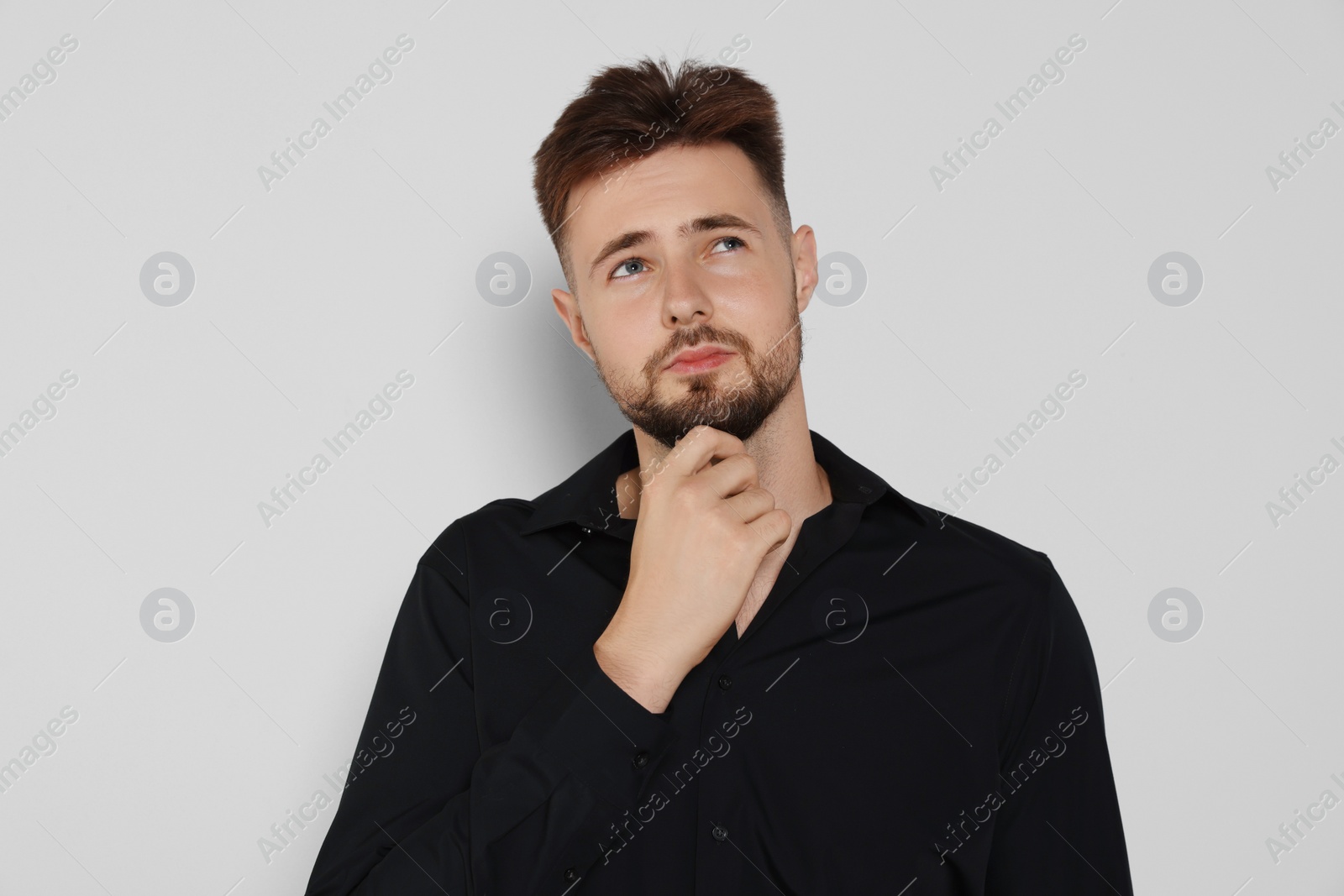 Photo of Thoughtful man in black shirt on light grey background