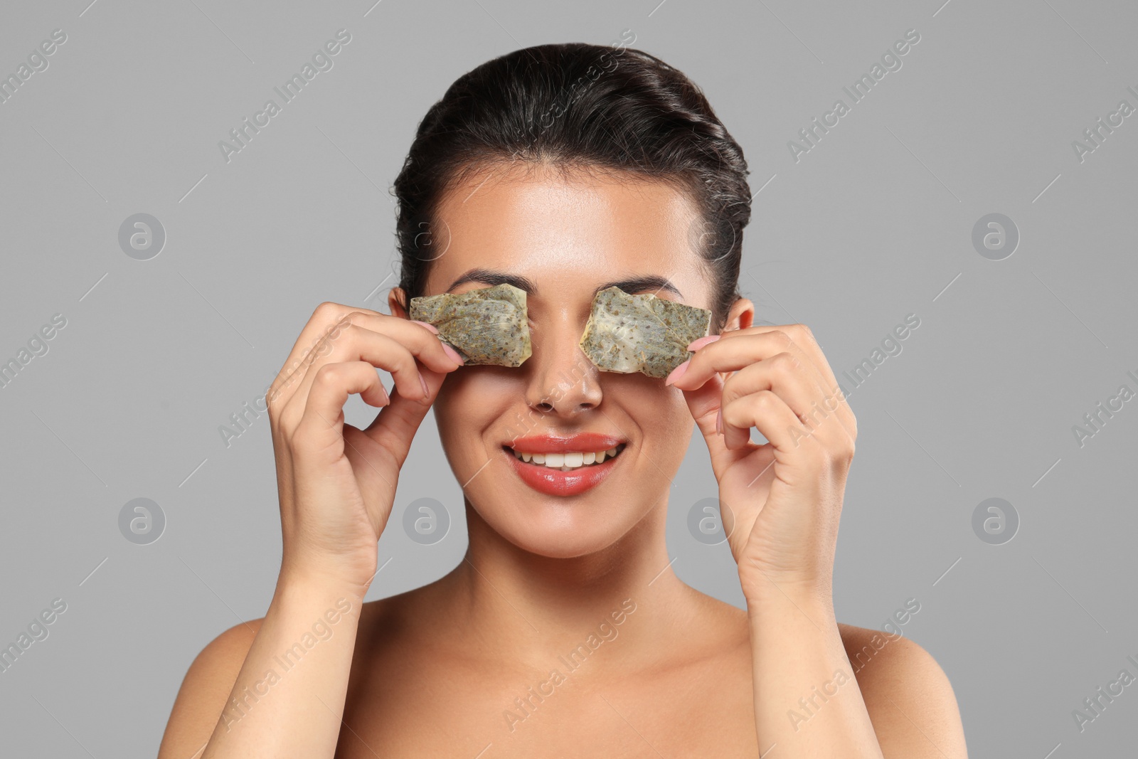 Photo of Woman covering eyes with tea bags on grey background. Skin care