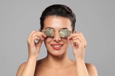 Photo of Woman covering eyes with tea bags on grey background. Skin care