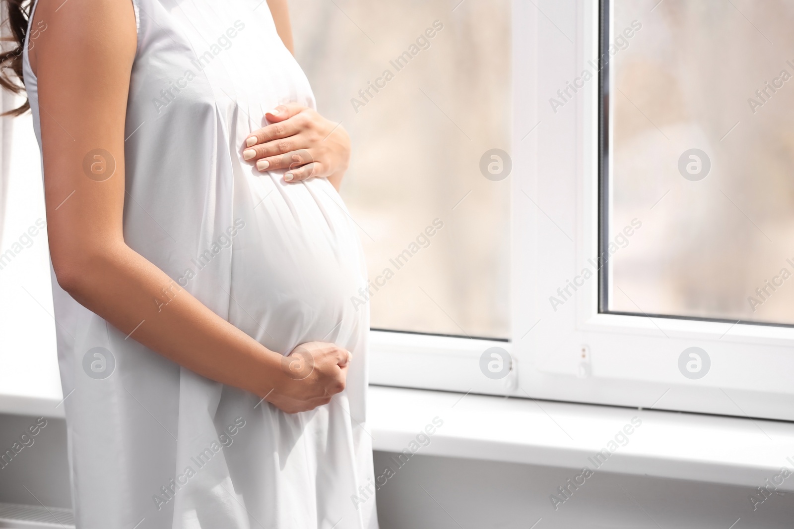 Photo of Beautiful pregnant woman near window at home