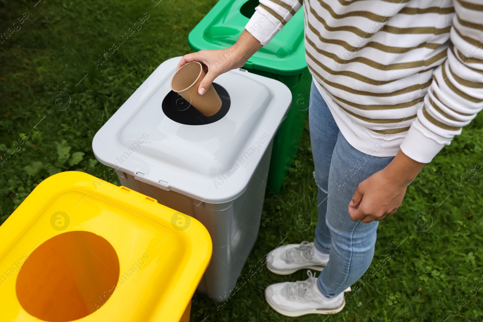 Photo of Woman throwing coffee cup into recycling bin outdoors, closeup