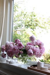 Beautiful pink peonies in vase on window sill, space for text. Interior design