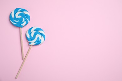 Sticks with bright lollipops on pink background, flat lay. Space for text