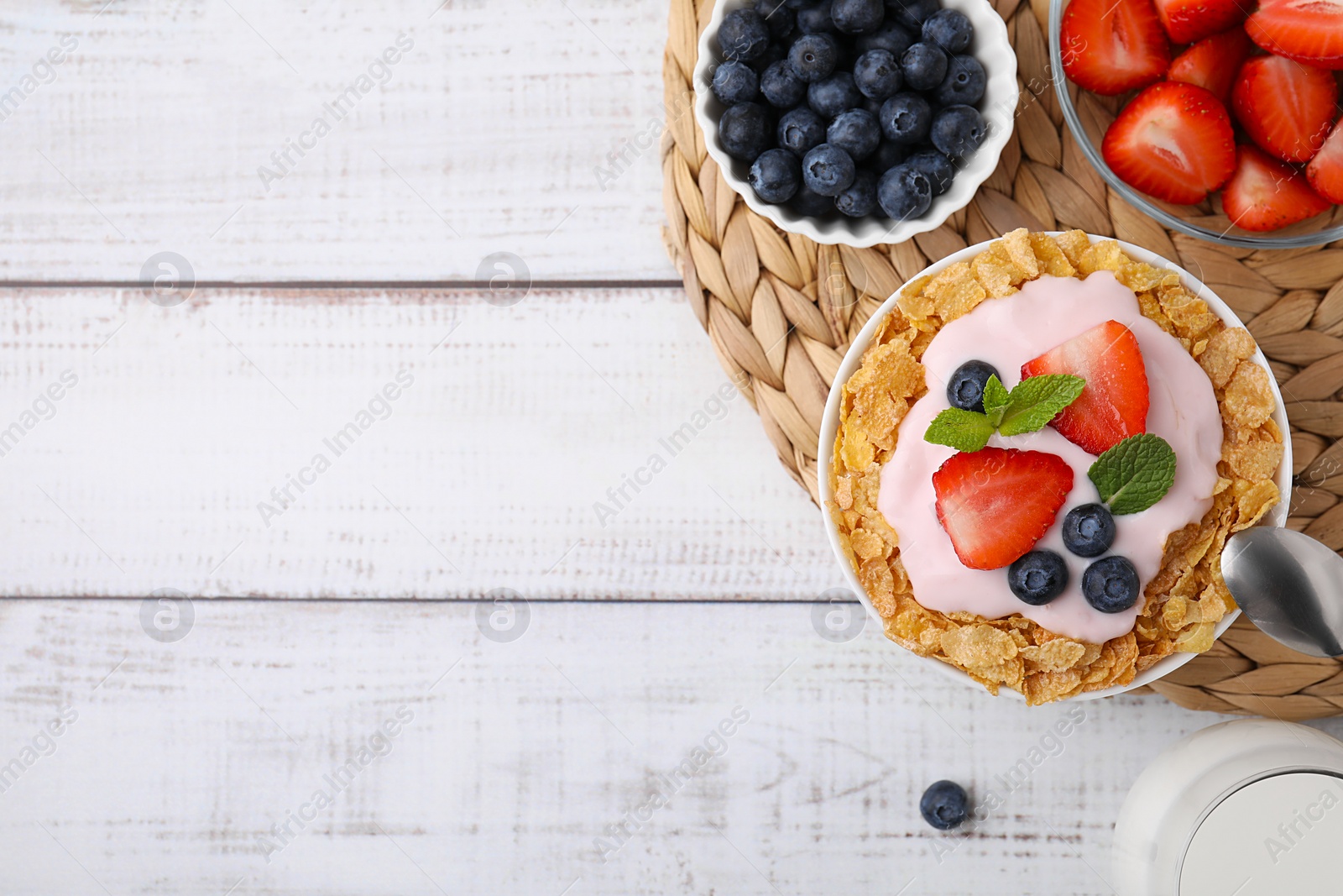 Photo of Delicious crispy cornflakes, yogurt and fresh berries served on white wooden table, flat lay with space for text. Healthy breakfast