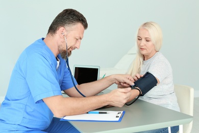 Photo of Male medical assistant measuring female patient blood pressure in clinic