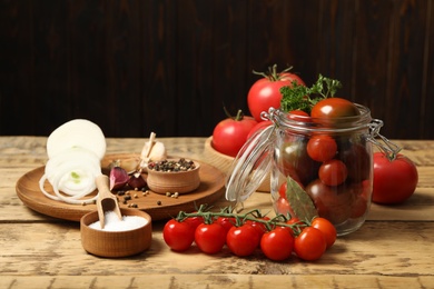 Photo of Pickling jar with fresh ripe cherry tomatoes and spices on wooden table