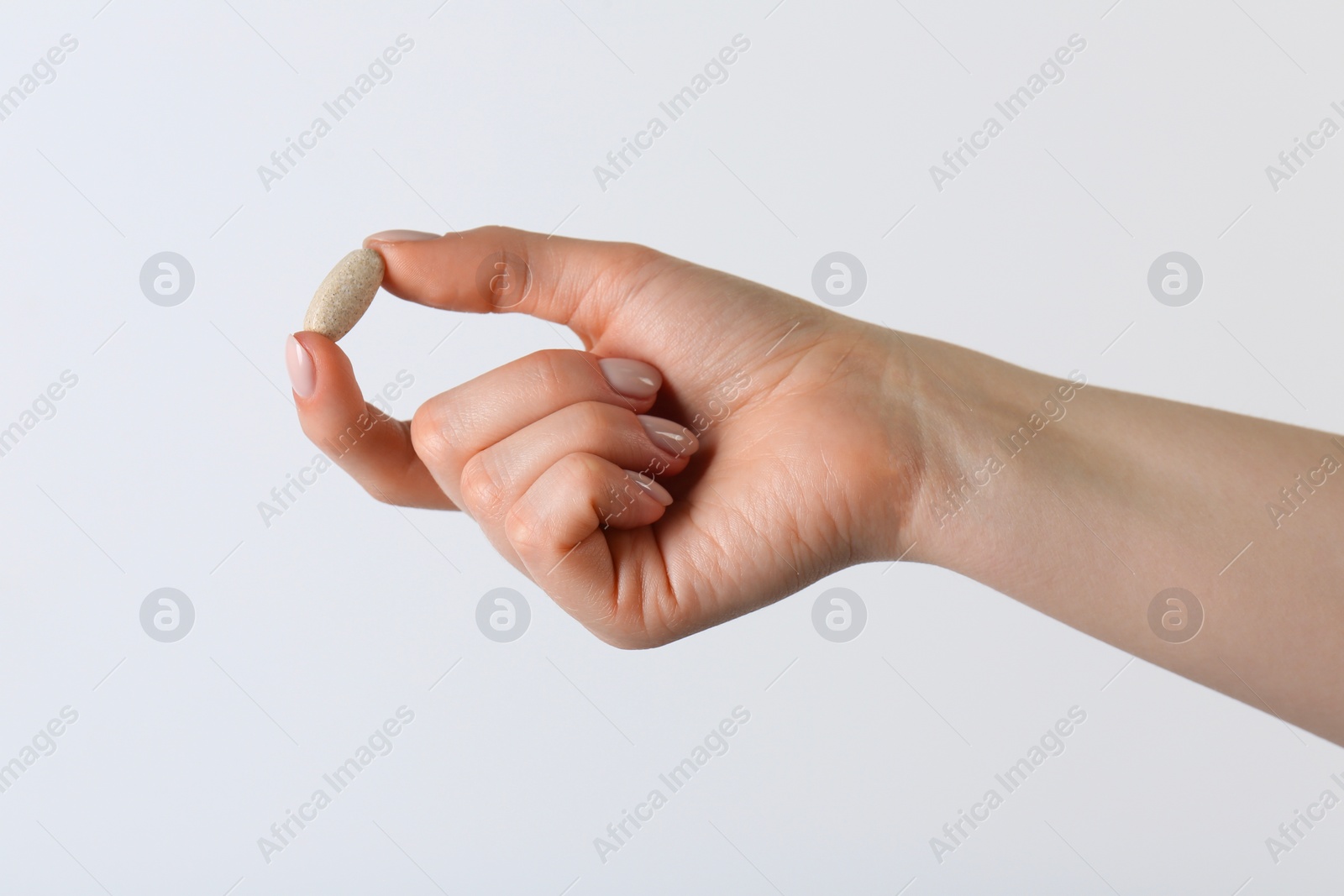 Photo of Woman holding vitamin pill on white background, closeup. Health supplement