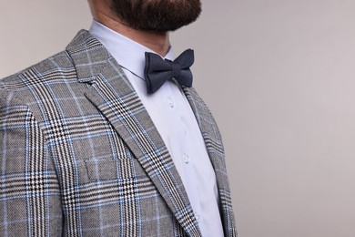 Man in suit, shirt and bow tie on grey background, closeup. Space for text