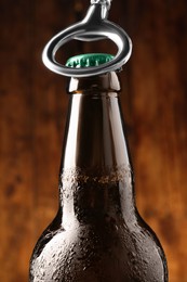 Photo of Opening bottle of beer on wooden background, closeup