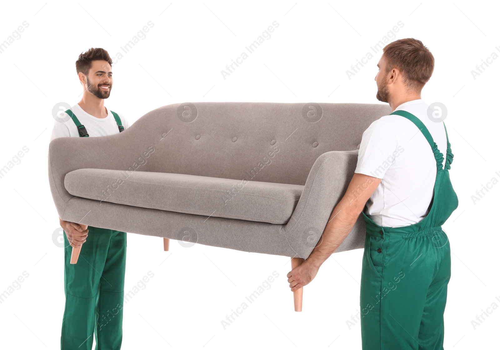 Photo of Young workers carrying sofa isolated on white. Moving service