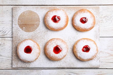 Photo of Hanukkah doughnuts with jelly and sugar powder on wooden table, flat lay