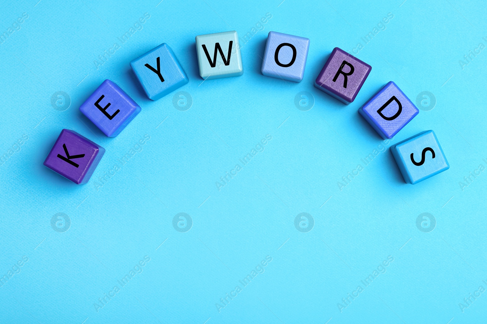 Photo of Colorful cubes with word KEYWORDS on light blue  background, flat lay. Space for text