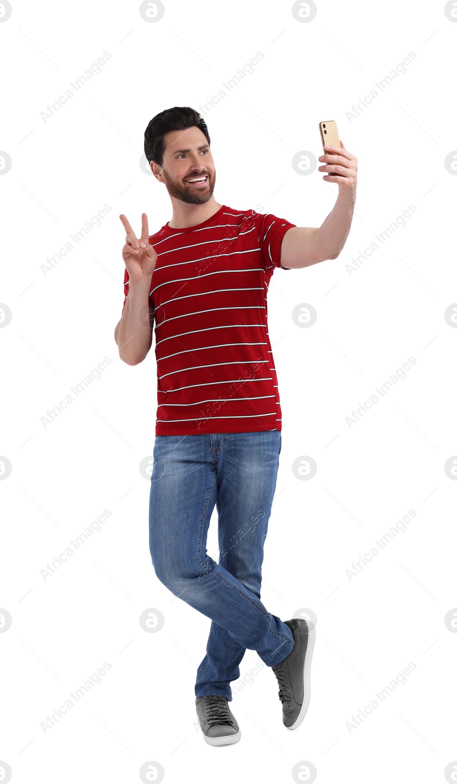 Photo of Smiling man taking selfie with smartphone and showing peace sign on white background