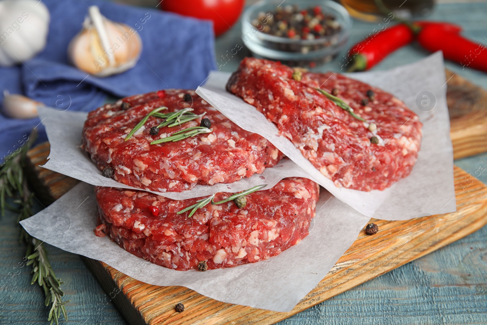 Photo of Raw meat cutlets for burger on blue wooden table