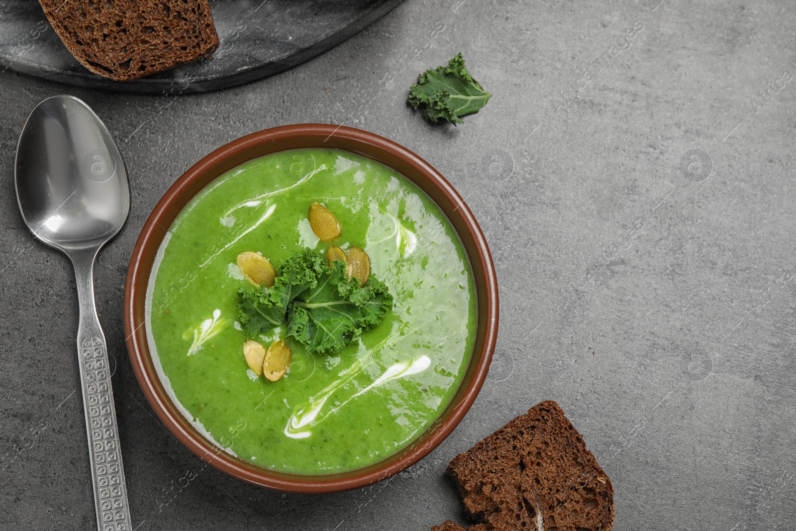 Photo of Tasty kale soup served on grey table, flat lay. Space for text