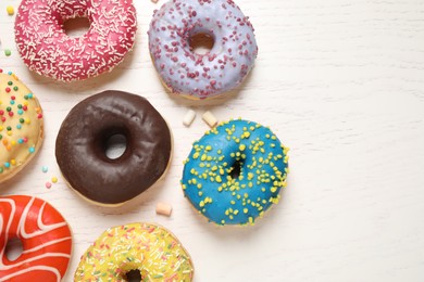 Photo of Delicious glazed donuts on white wooden table, flat lay