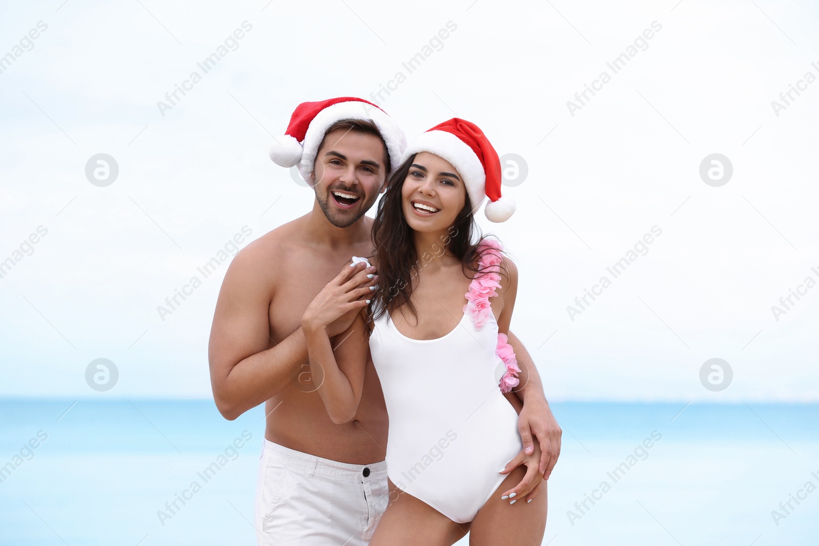 Photo of Happy young couple with Santa hats together on beach