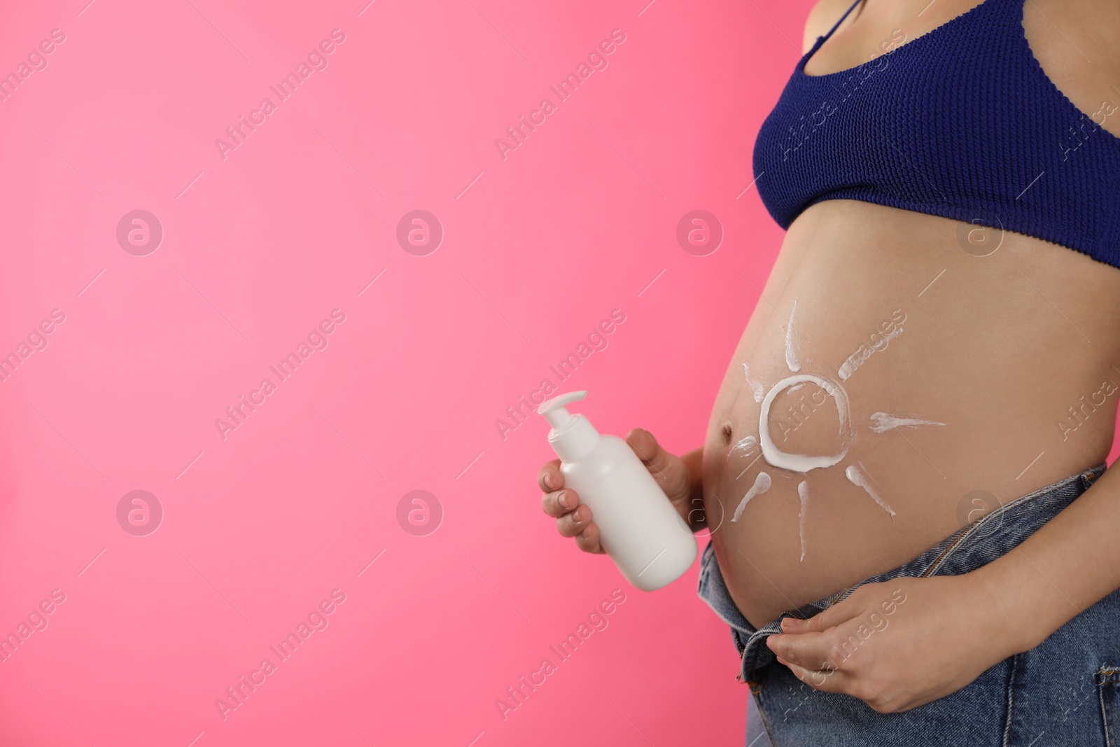 Photo of Young pregnant woman with sun protection cream on pink background, closeup. Space for text