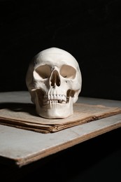 Photo of Human skull and old book on table against black background